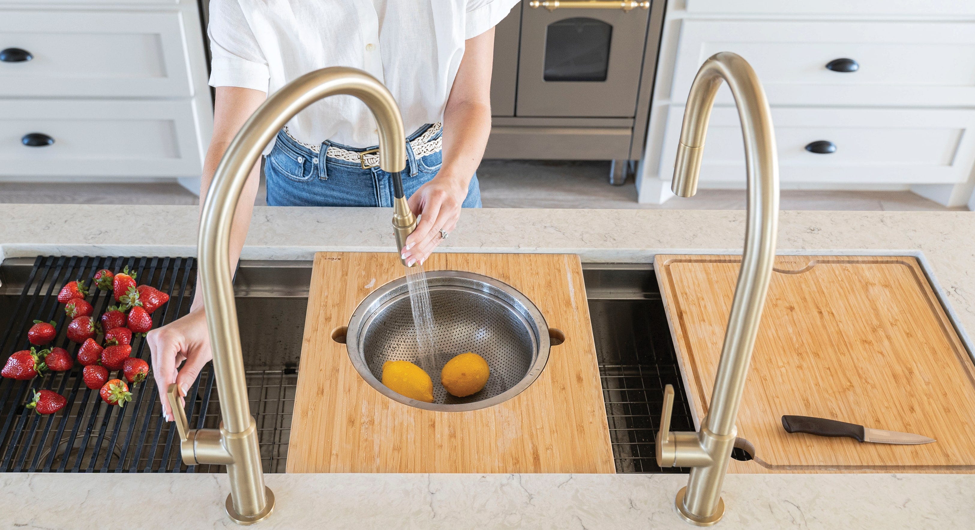 Kore Workstation Kitchen Sink Oletto Pull-Down Kitchen Faucet in Brushed Gold wash on Orange in Cutting Board, Strawberry on Dish Drying Rack, Knife